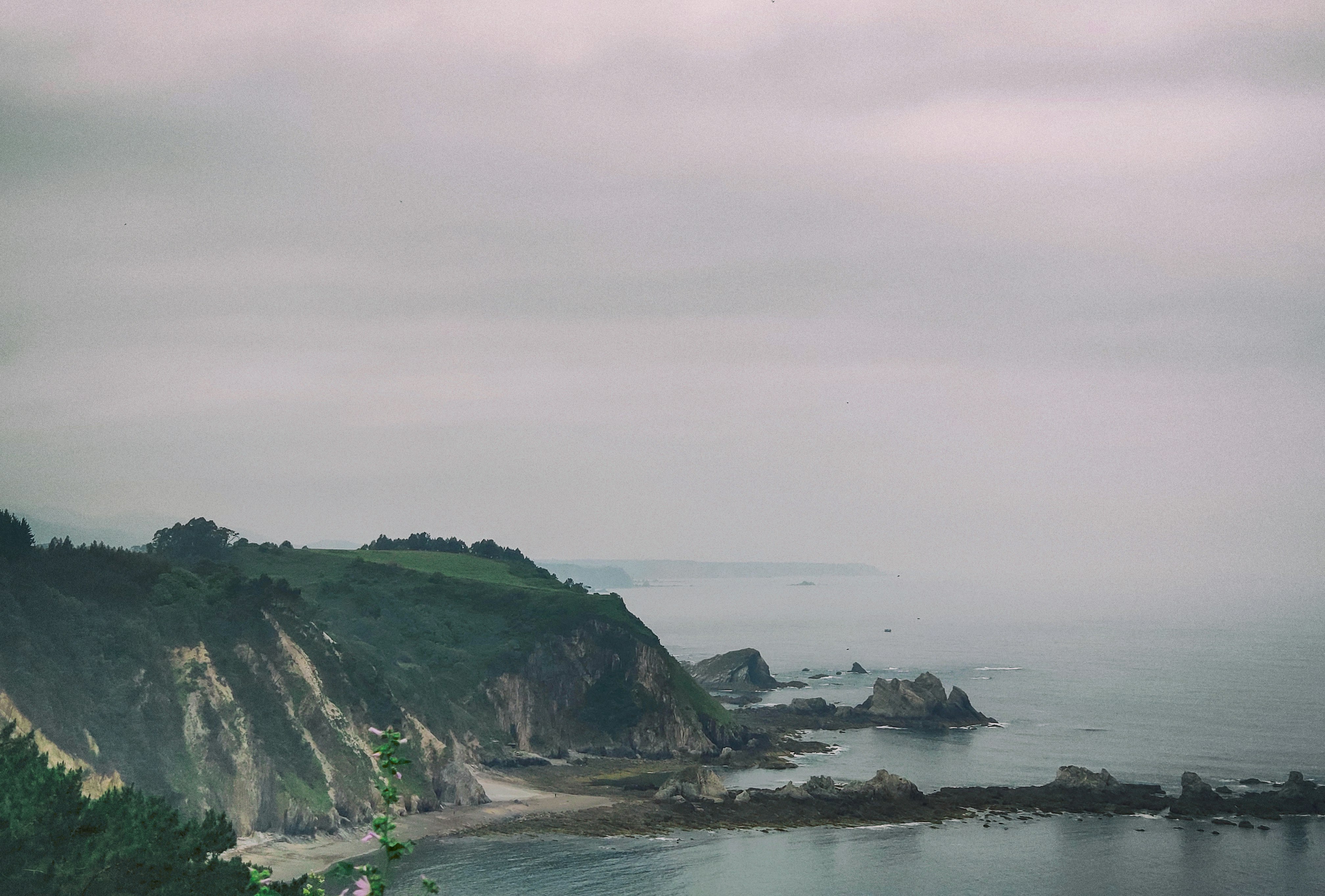 mountain by shore under gray skies